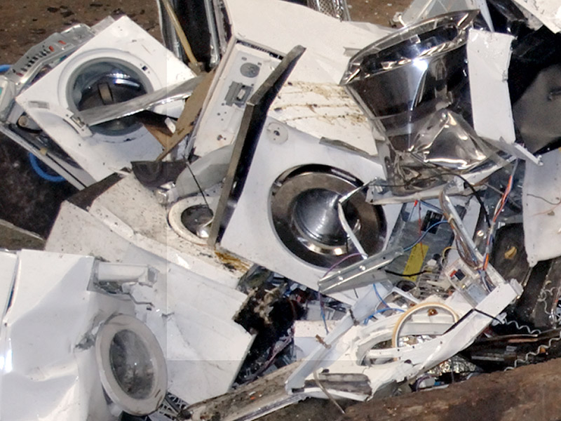 Zerlegte und gestapelte Waschmaschinen und Haushaltsgeräte auf einem Recyclingplatz – steht für fachgerechte Demontage und Rückgewinnung von Wertstoffen im eRecycling